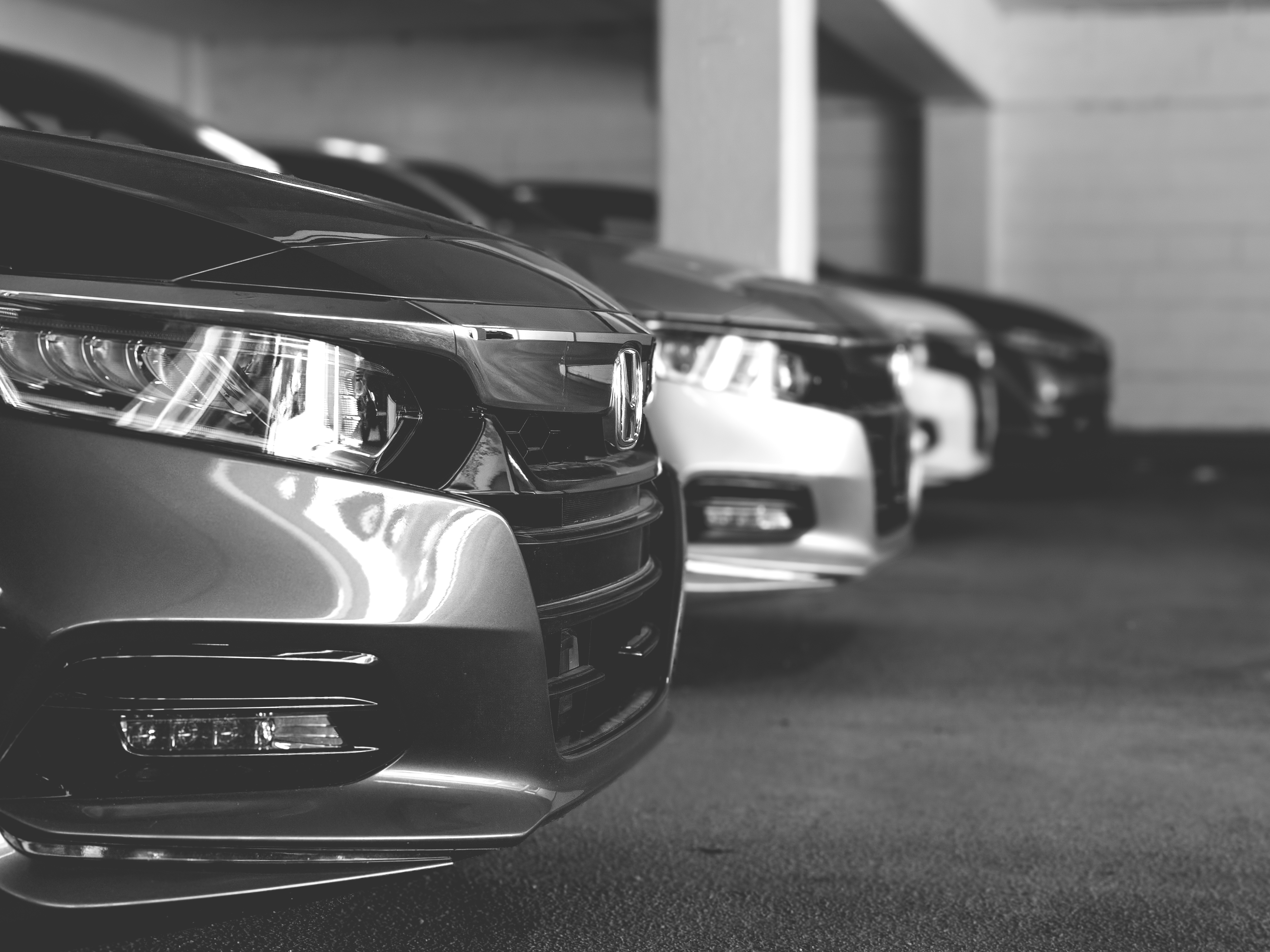 black and white photo of line of parked cars in garage