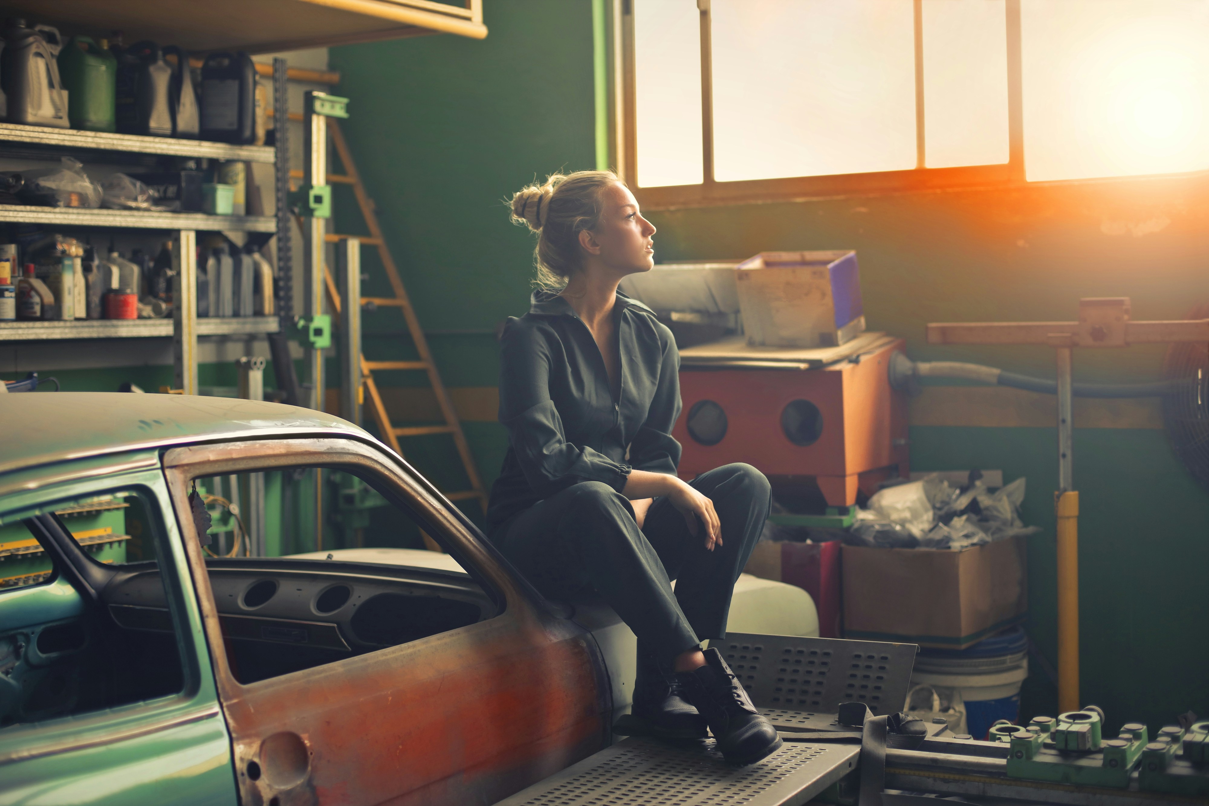 woman sitting on old car inside art studio