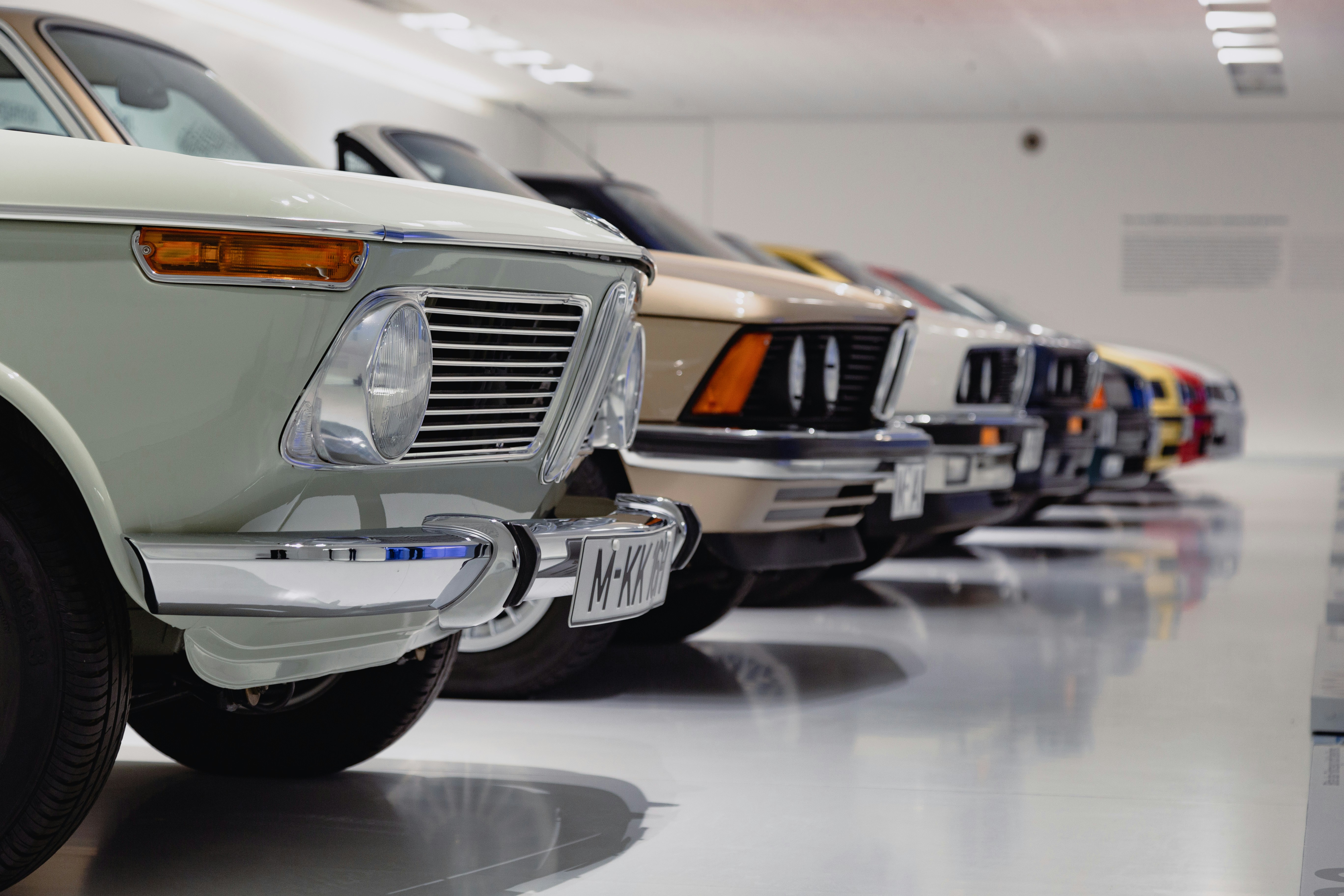 Row of vintage cars inside a white room