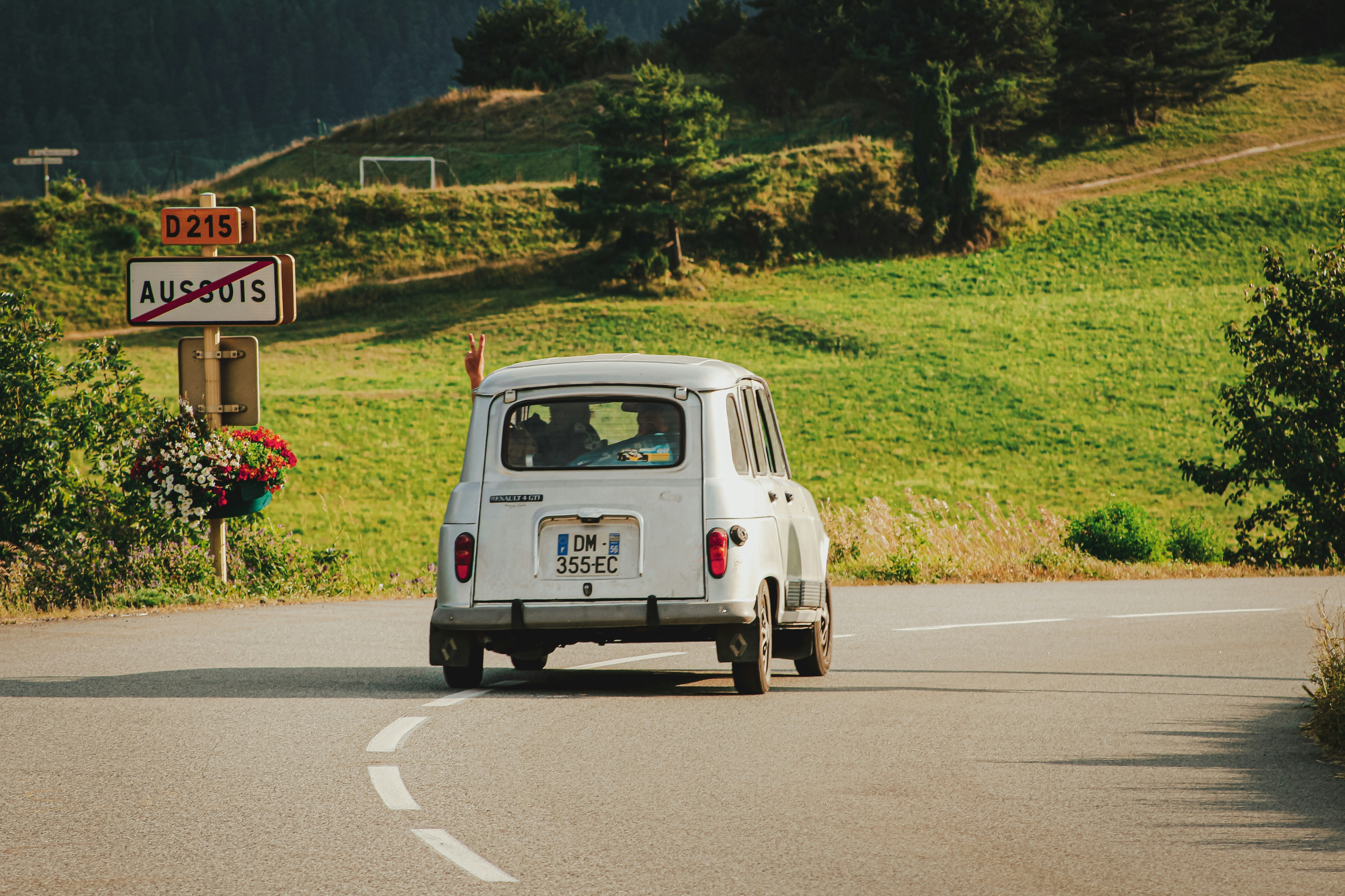 Old white car in Europe, hand flashing peace sign out the window