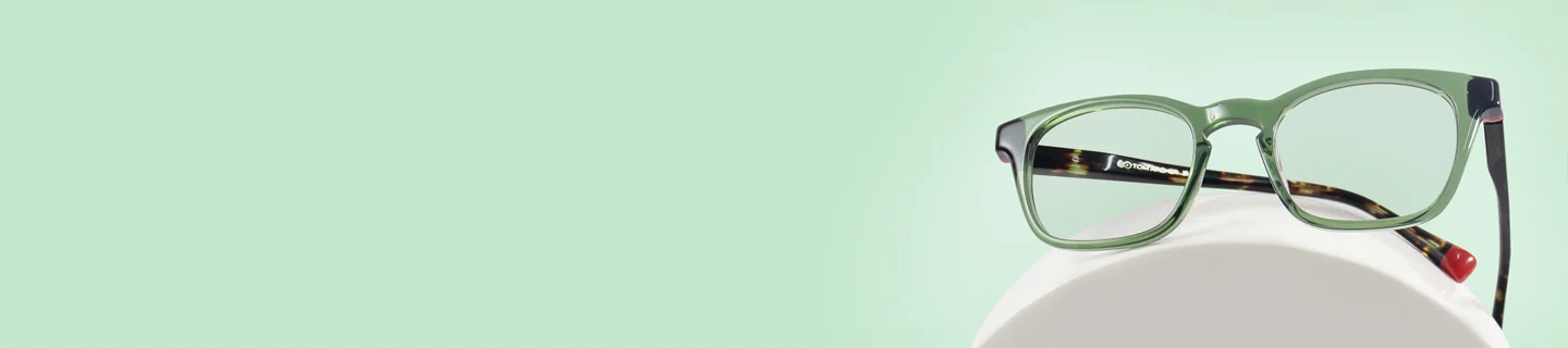 The image features a pair of green eyeglasses with black and tortoiseshell temples. It has a rectangular shape and is placed over a white stand against a light green background. It also has text saying Green Glasses, discount offer and Trustpilot Reviews.