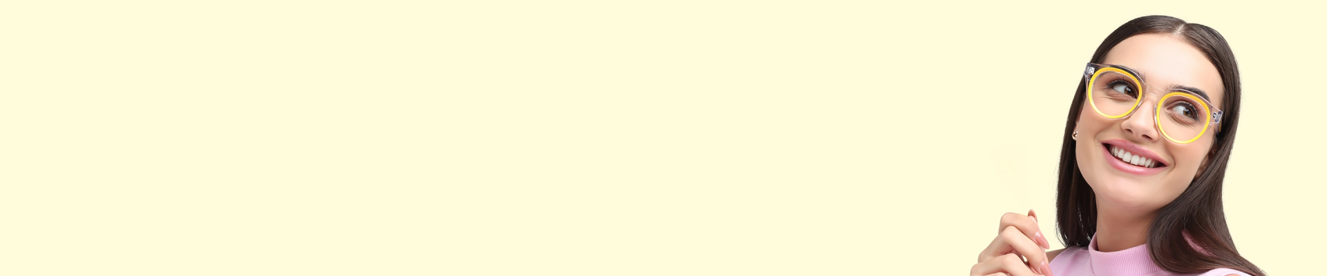 A smiling woman wearing stylish, oversized yellow and black round glasses looks up and to the side against a pale yellow background.