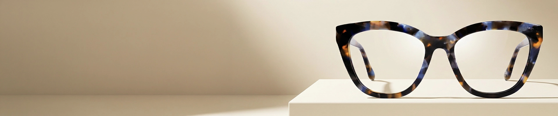 Stylish cat-eye glasses featuring a unique gradient frame that fades from maroon corners to a clear pink base, set on a soft pink background.