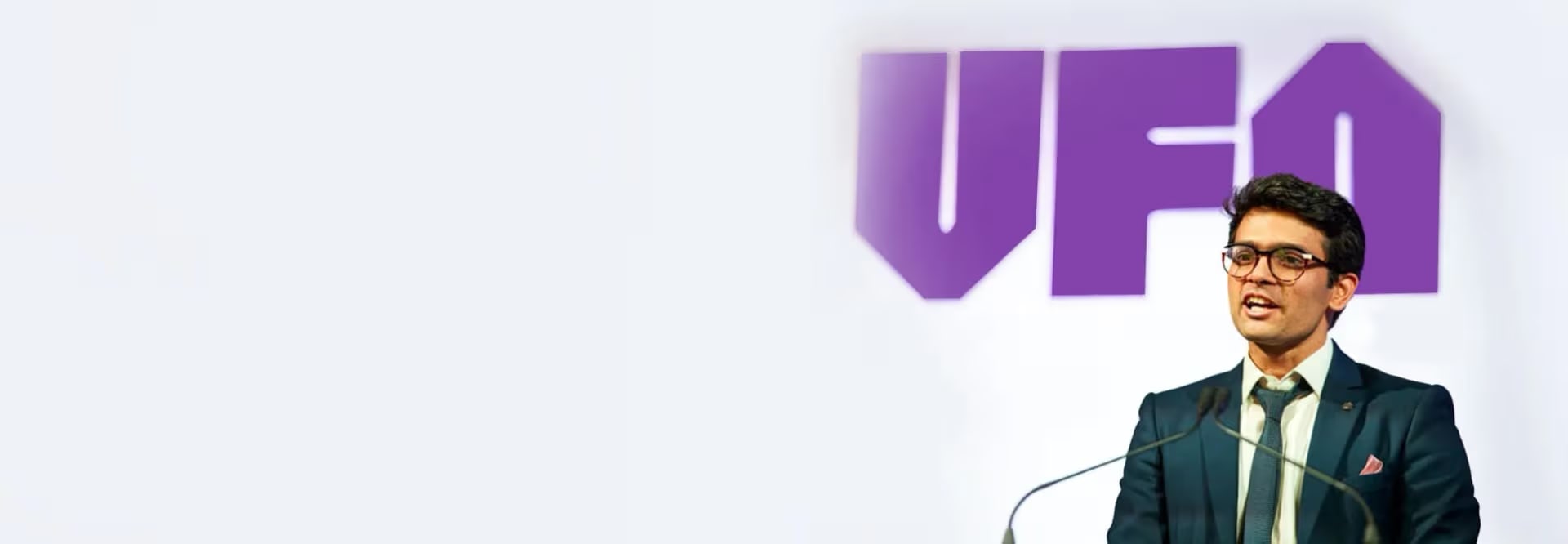 Sid Sethi, Specscart’s founder, giving a speech in formal attire at the Venture Further Awards, University of Manchester. The background features a large purple VFA logo and event branding, alongside an Excellent Trustpilot rating on the left.