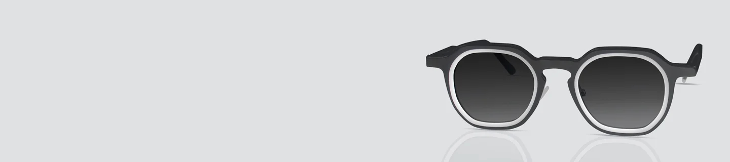 Geometric black sunglasses with a distinctive keyhole bridge and white inner rim detail, featuring dark tinted lenses for a bold modern style.