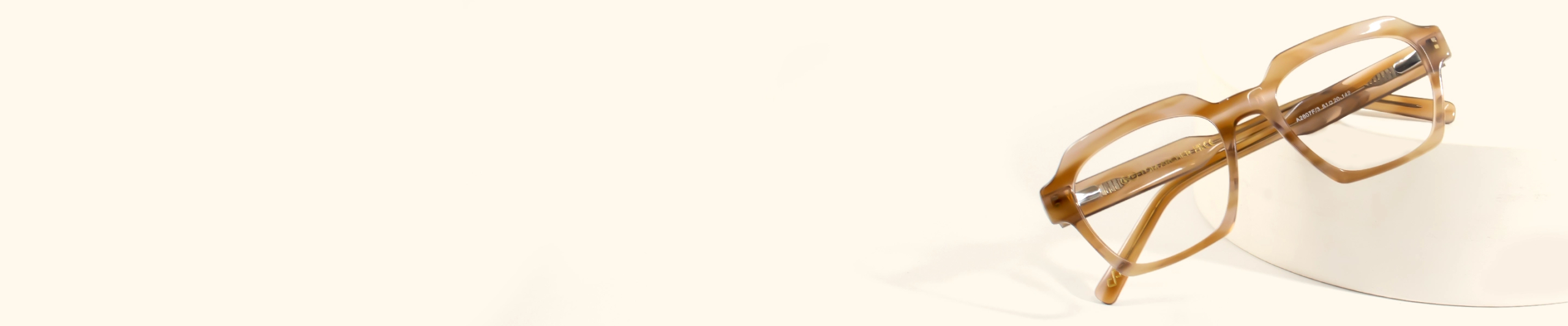 Image featuring a pair of modern, thick-rimmed brown tortoiseshell glasses with clear lenses, showcasing their reflection on a light, smooth surface, featuring brown glasses page.