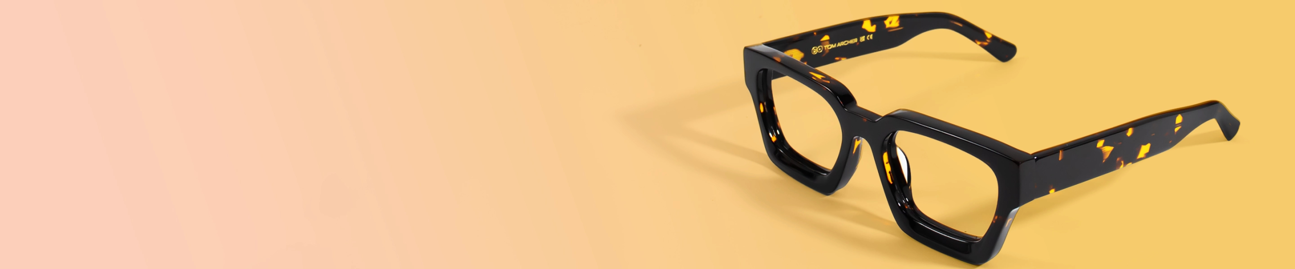 Thick-rimmed rectangular glasses in glossy black acetate with bold yellow tortoiseshell accents, displayed against a solid pale yellow background. The glasses have clear, non-prescription lenses, showcased as fashionable fake glasses for style without vision correction.