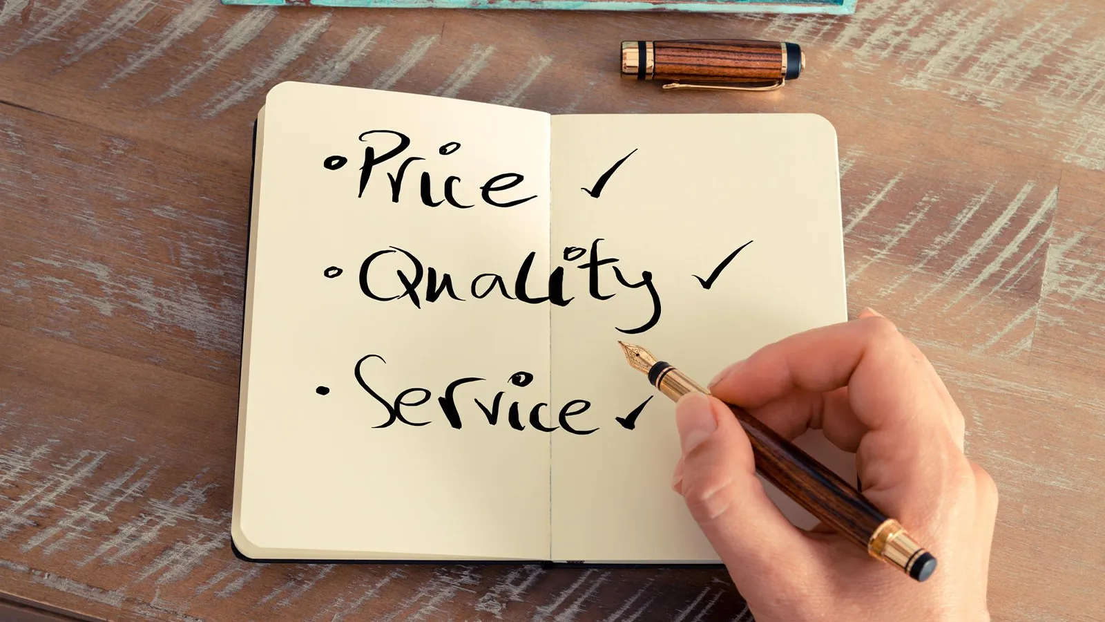 An Image featuring a notebook placed over a wooden table with written notes like Price, Quality and Service as a checklist. There is also a hand-holding pen and cap.