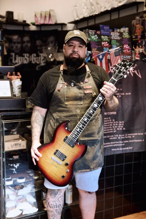 Manny holding a guitar inside SuperHet Coffee
