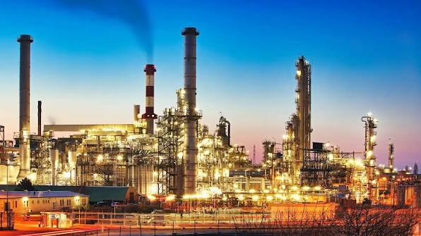 A modern oil refinery in India with large storage tanks and refining units.