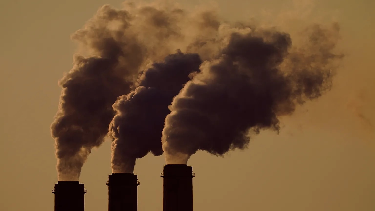 A globe surrounded by industrial smoke and renewable energy sources.
