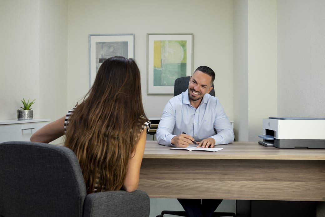 El doctor Bacinschi conversando y tomando notas durante la consulta con una paciente.