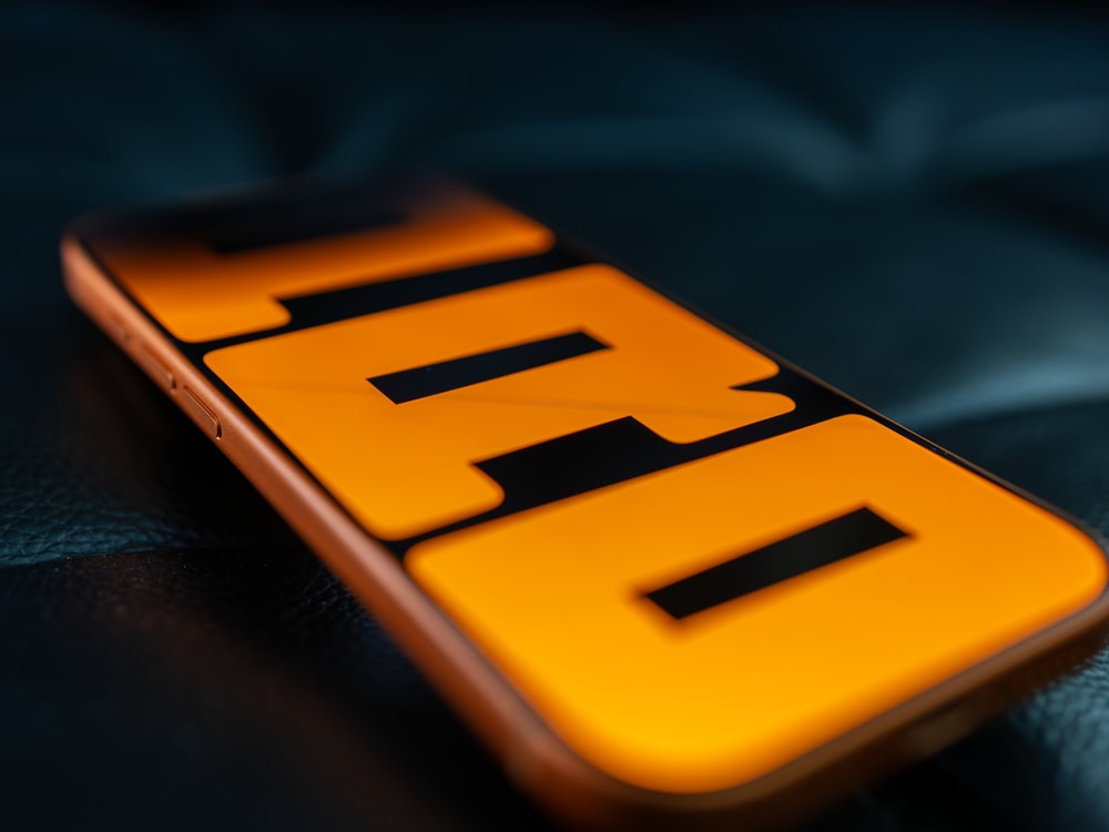 Photo of Apple iPhone 17 Pro in Cosmic Orange with wallpaper that displays 'PRO', written vertically.