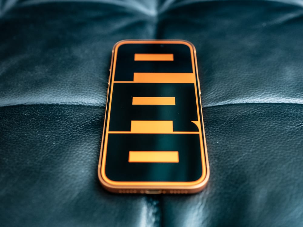 Photo of Apple iPhone 17 Pro in Cosmic Orange with wallpaper that displays 'PRO', written vertically.