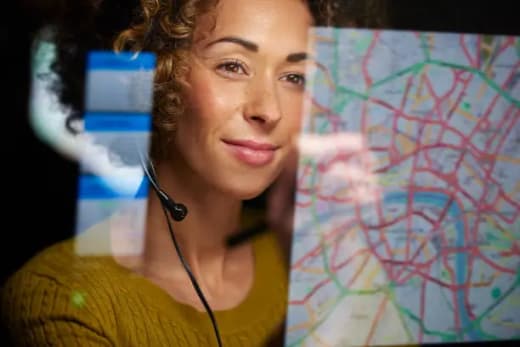Freight coordinator with headset reviewing routes and map data — UK logistics control