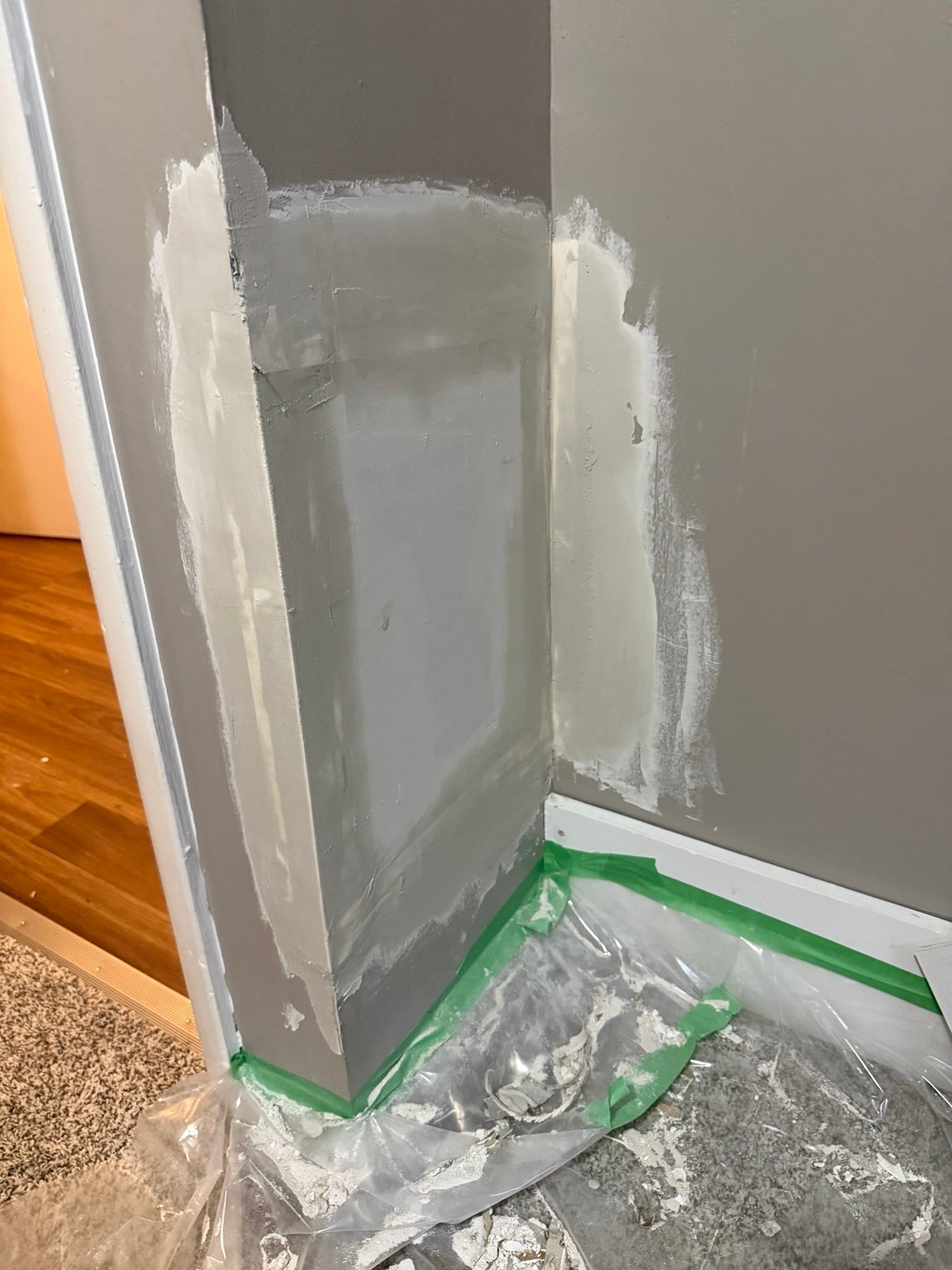 Completed interior drywall patch with taping knife nearby