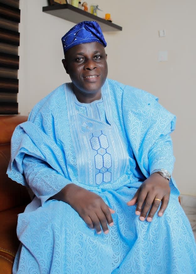 Comrade Ayeola in a seated sky-blue agbada portrait