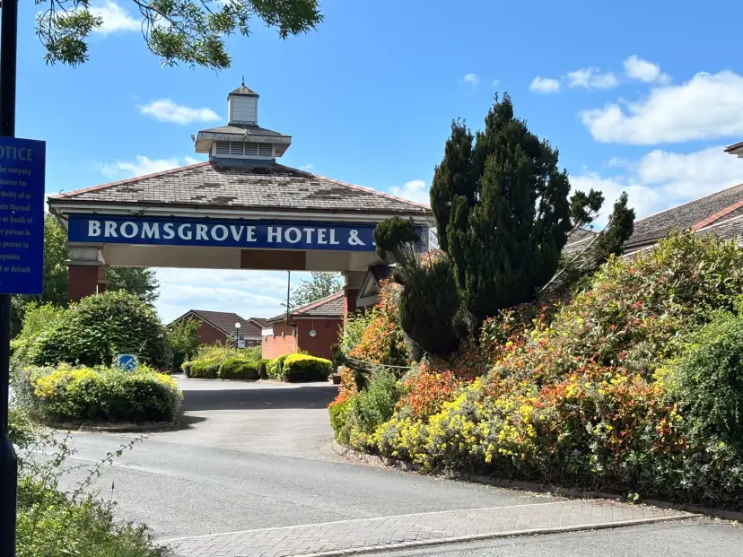 Bromsgrove Hotel and Spa entrance and grounds viewed from the A38 approach, showing hotel signage, green foliage and the dedicated taxi pull-in bay