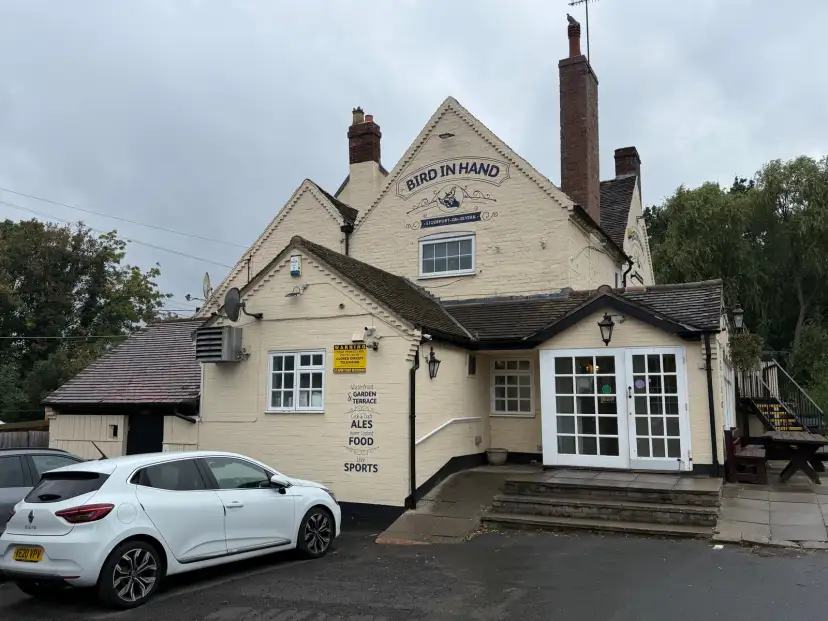 The Bird in Hand public house viewed from the canal towpath, showing the 1700s heritage building, canalside green space, and surrounding trees in north Worcestershire