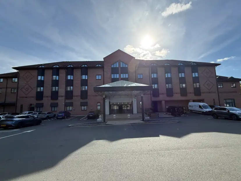 Crowne Plaza Solihull by IHG exterior viewed from the car park forecourt, modern glass and steel facade with automatic sliding doors and step-free entrance