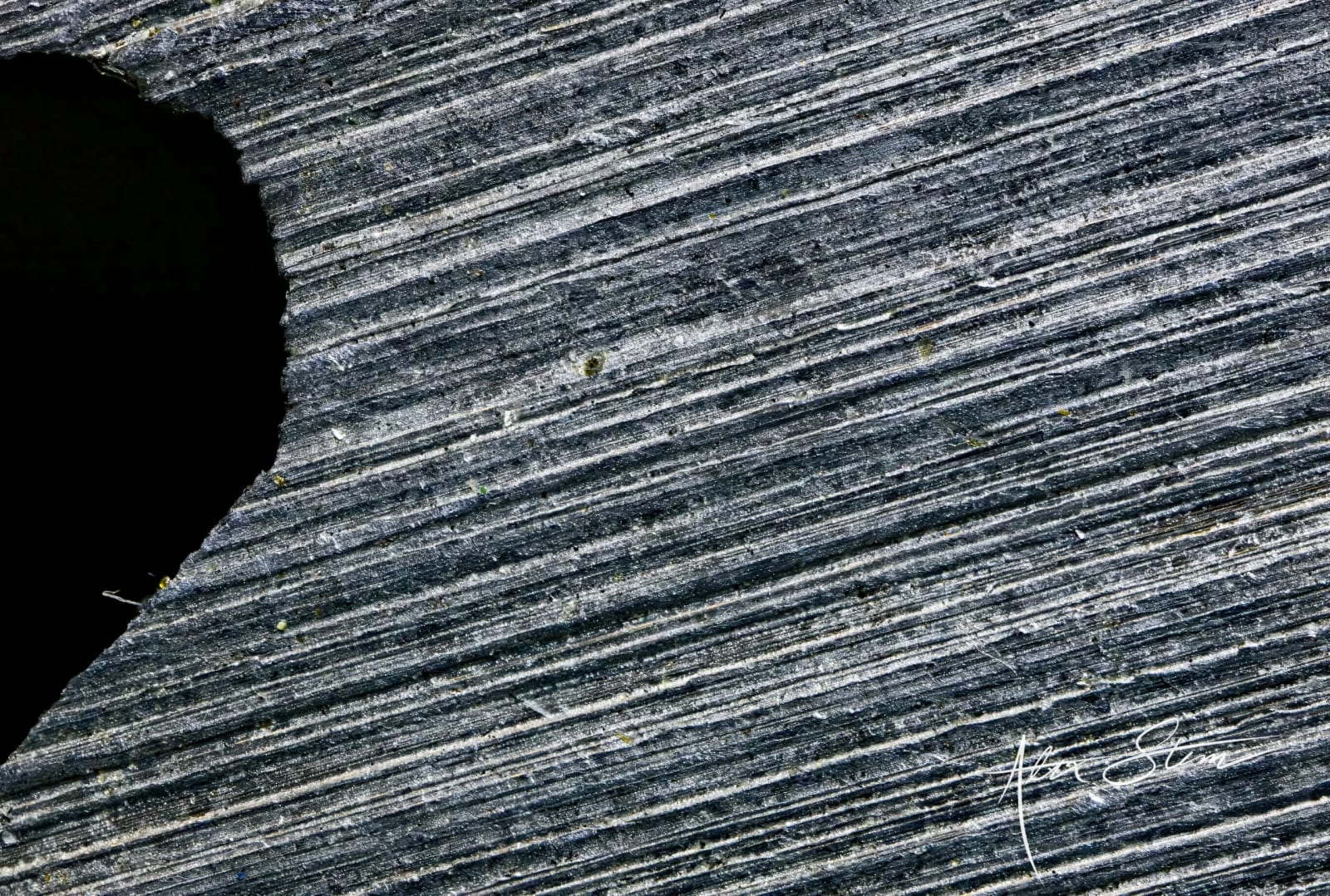 The image depicts a textured, layered surface with diagonal lines and patterns, creating a visually striking and abstract composition.