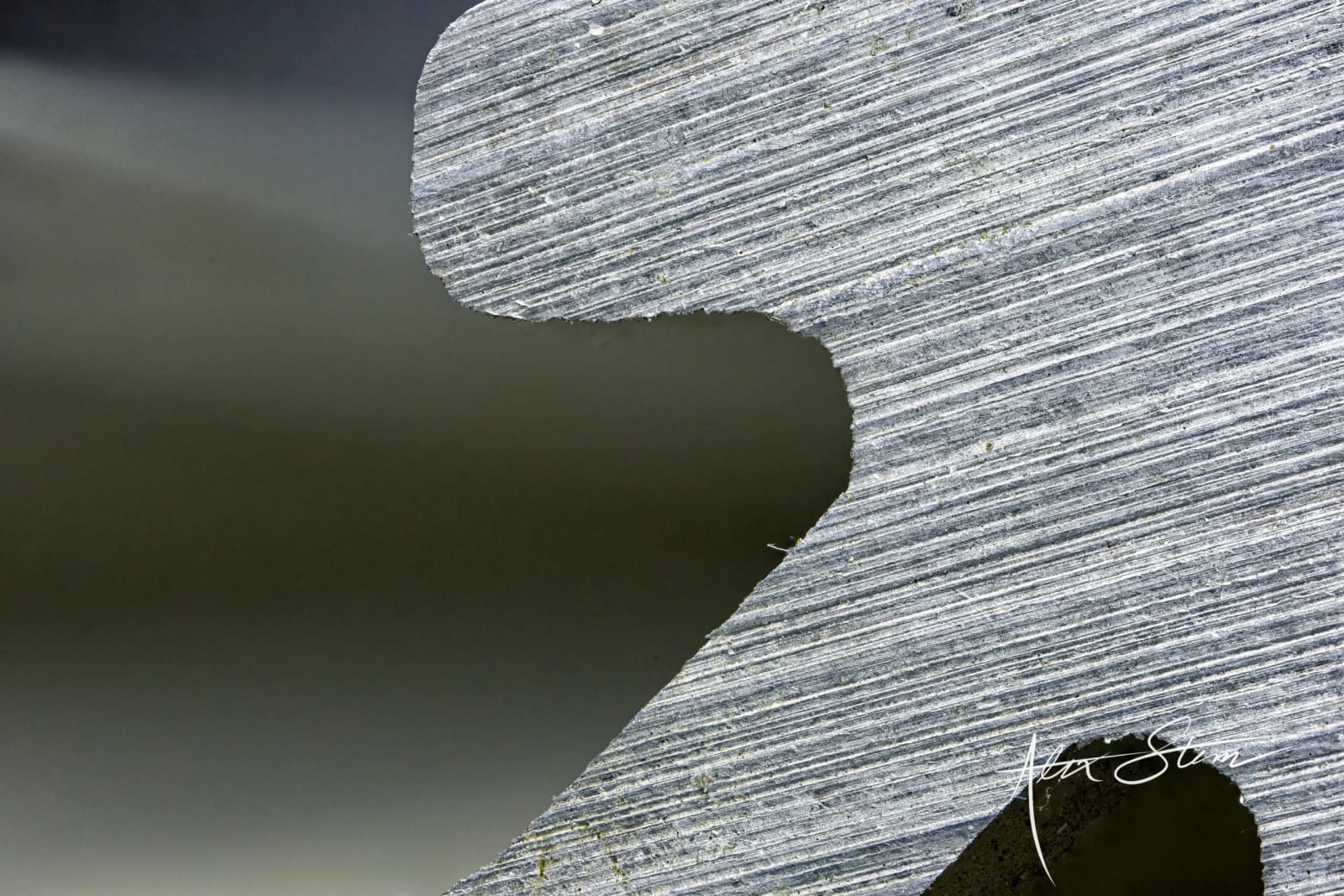 A close-up view of a textured, layered surface with distinct striations and a dark, blurred background.