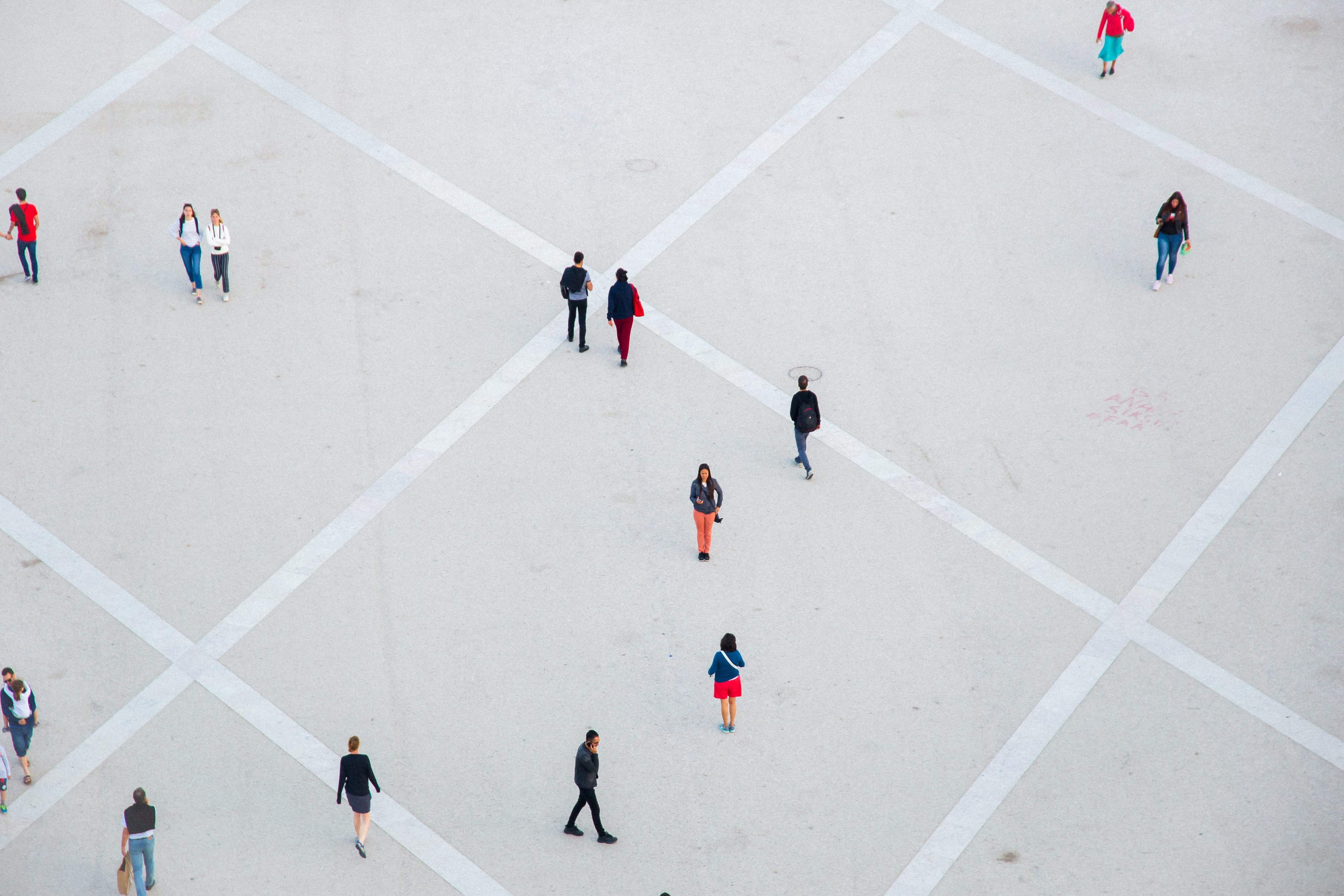 People walking across a plaza with a grid pattern