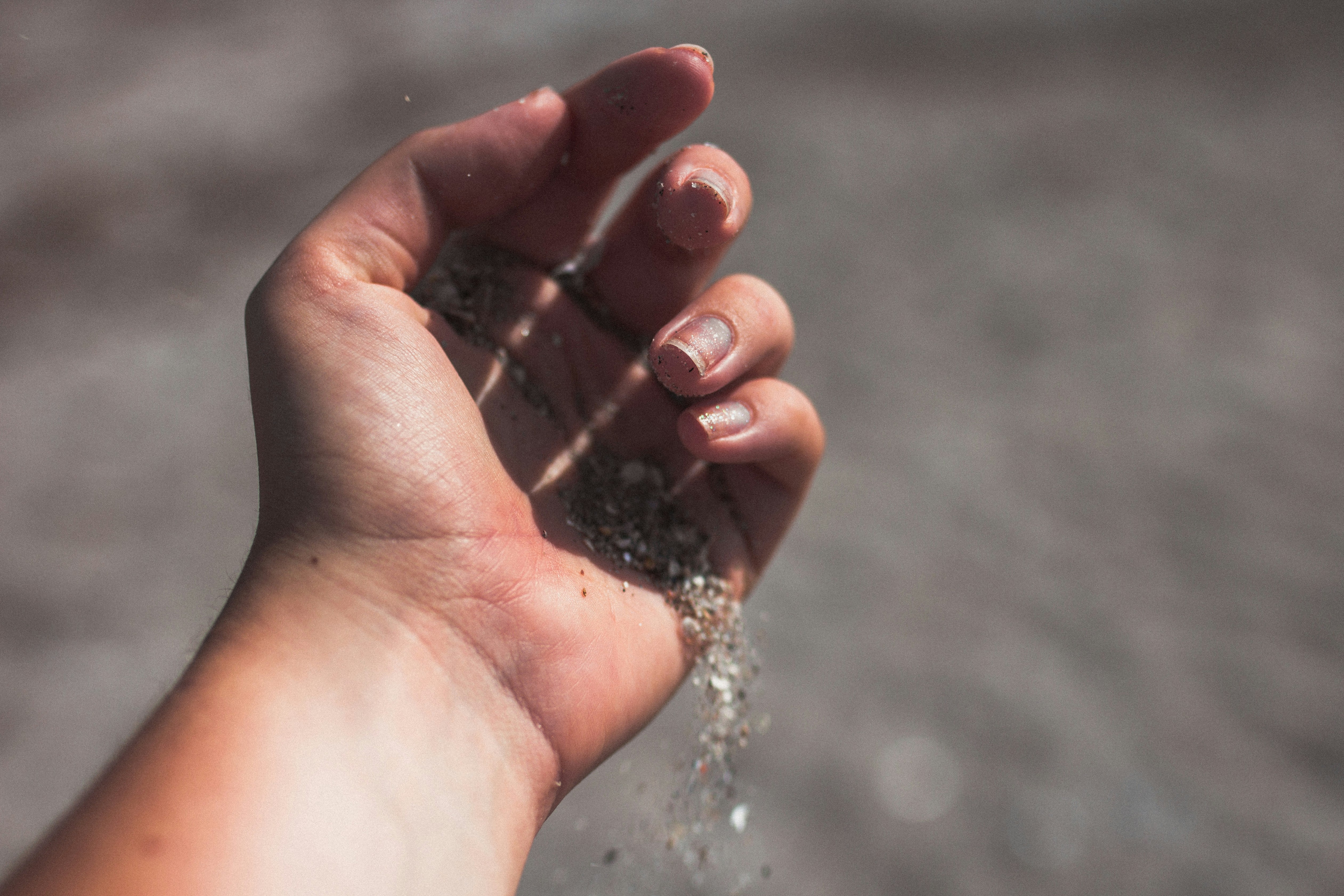 Sand falling through an open hand on a beach