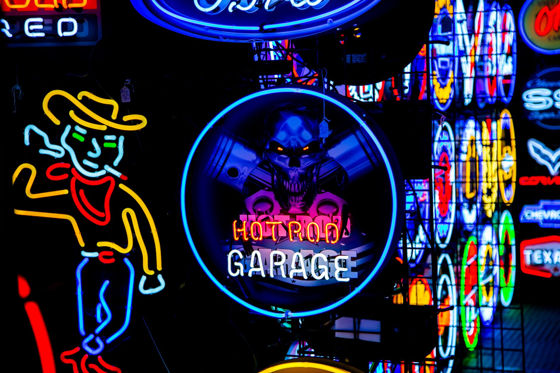 Bright signs including one reading Hot Rod Garage, glowing in a colorful night street scene.