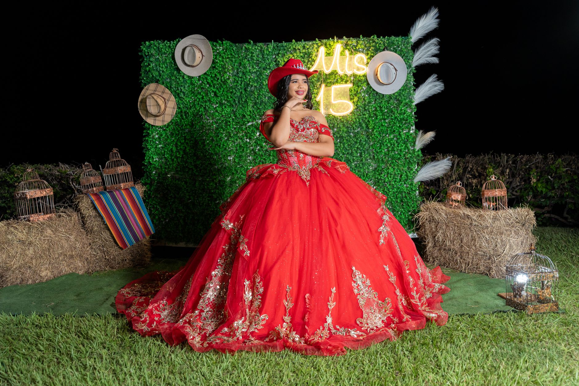 A young woman in a flowing red gown celebrates proudly outdoors at night.