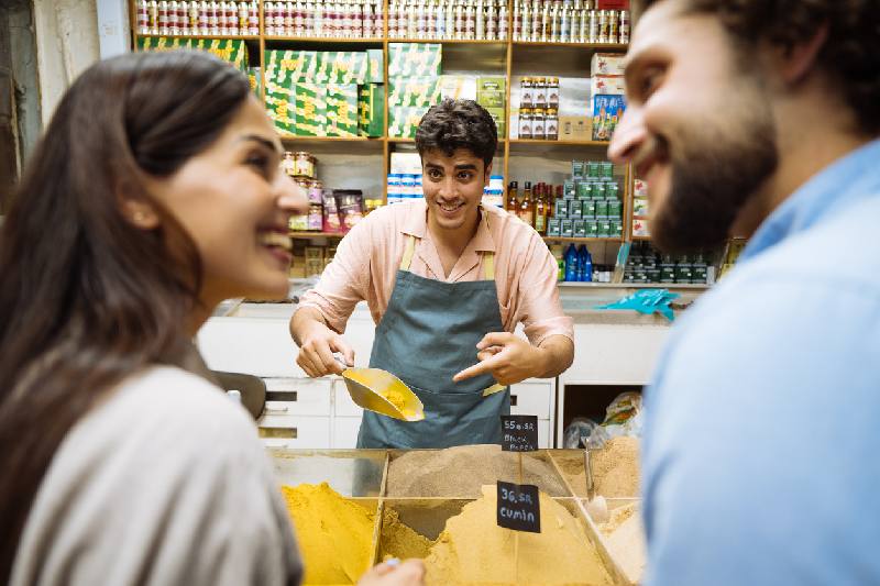 Vendedor mostrando especias a una pareja en un mercado