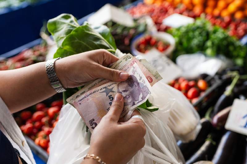 Manos pagando con libras egipcias en un mercado de verduras