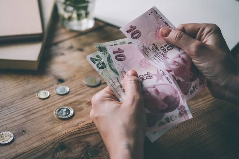Manos sosteniendo billetes y monedas sobre madera