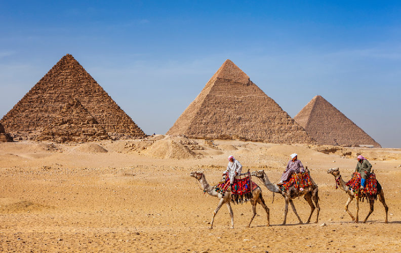 Beduinos montando camellos frente a las Pirámides de Giza