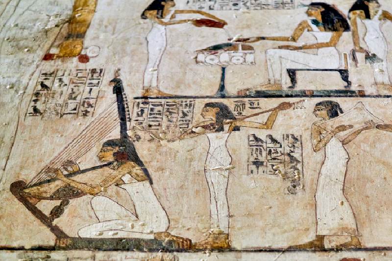 Músicas y danzarinas del Antiguo Egipto durante una celebración religiosa, representadas en un fresco con instrumentos tradicionales.