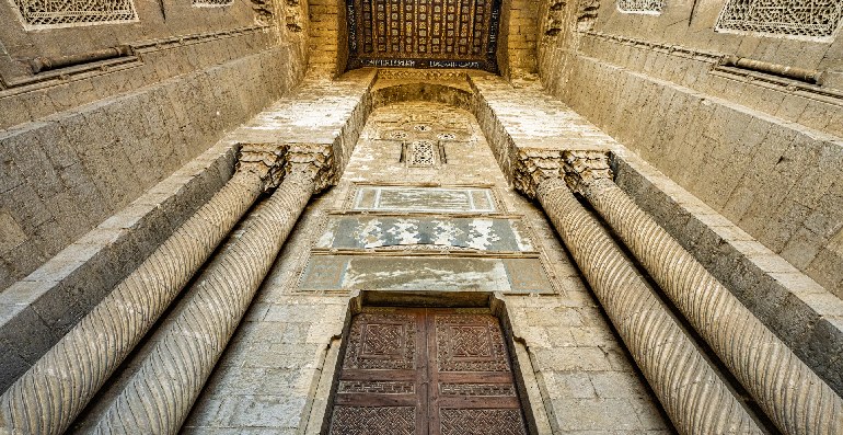 La mezquita Al-Rifai en el antiguo Cairo, Egipto. Una antigua sala de piedra con intrincadas tallas y una gran puerta de madera.