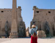 Una donna bionda con un cappello di paglia guarda l'ingresso del Tempio di Luxor