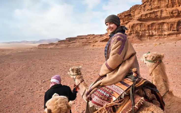 una ragazza cavalca un cammello a Wadi Rum, Cosa vedere in giordania