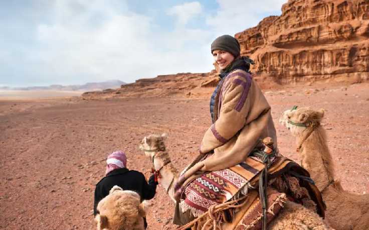 una donna cavalca il cammello al deserto, vestirsi in giordania