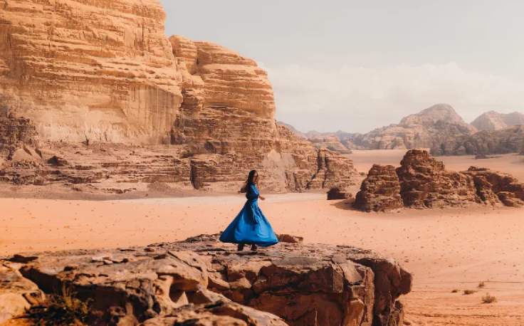donna con un abito blu che ammira il suggestivo paesaggio del wadi rum, visto per la giordania