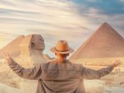 a happy traveller with a hat infront of pyramids if Giza