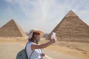 tourist woman takes selfie with pyramids of giza, Gems of Egypt and Nile Tour
