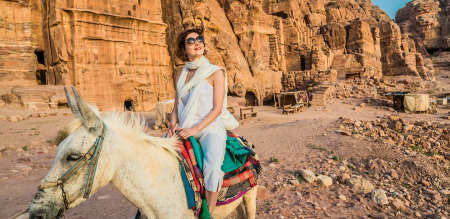 a woman wearing white dress riding a donkey in petra 