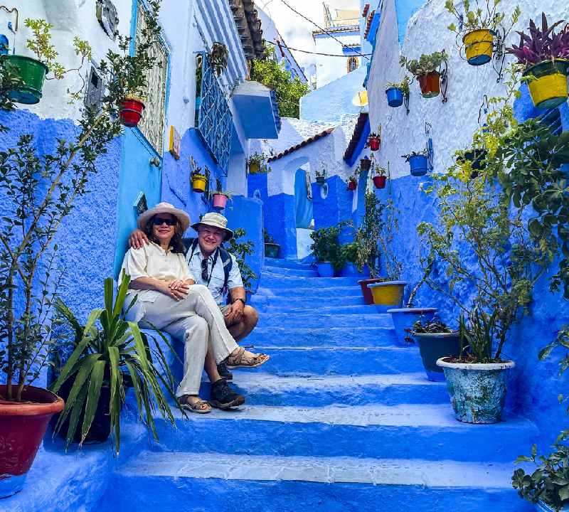 Casal maduro posando em uma escadaria em Chefchaouen, Marrocos. As coloridas muralhas azuis da cidade tornam esta cidade única.
