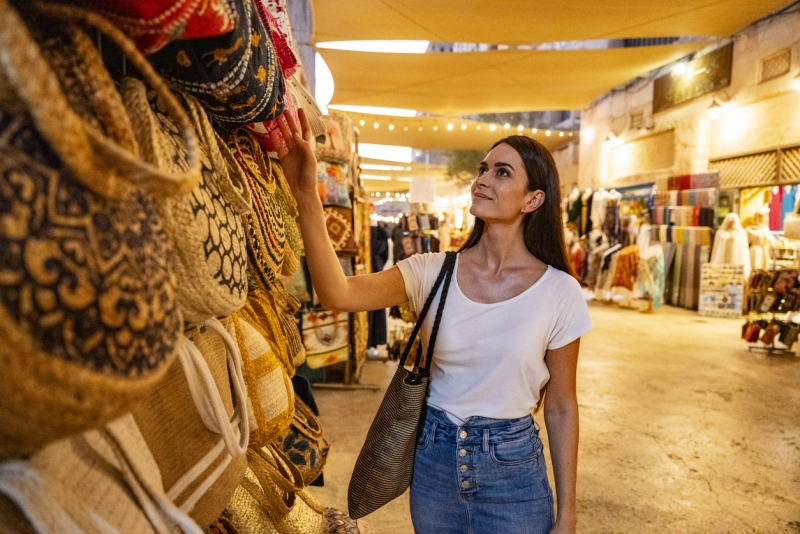 Mid adult female tourist looking at bags in Dubai souk