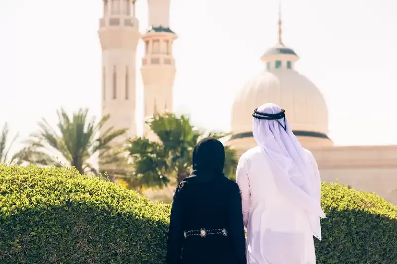 Coppia araba in piedi davanti a una moschea, moschea bianca abu dhabi