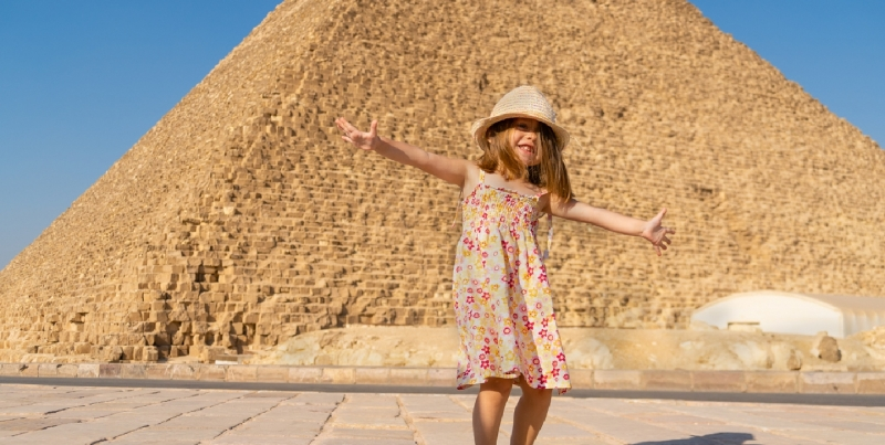 Linda niña bailando frente a la pirámide de Keops en la meseta de Giza.