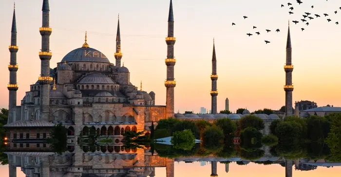 La Mezquita Azul al atardecer en Estambul, reflejada en el agua, destino icónico de nuestros paquetes a Turquía.