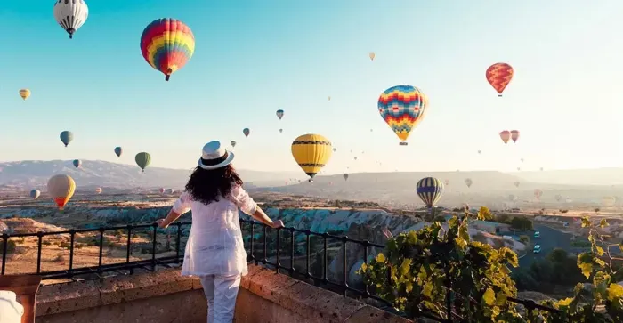 Mujer admirando globos aerostáticos al amanecer en Capadocia durante su viaje a Turquía, una experiencia inolvidable.