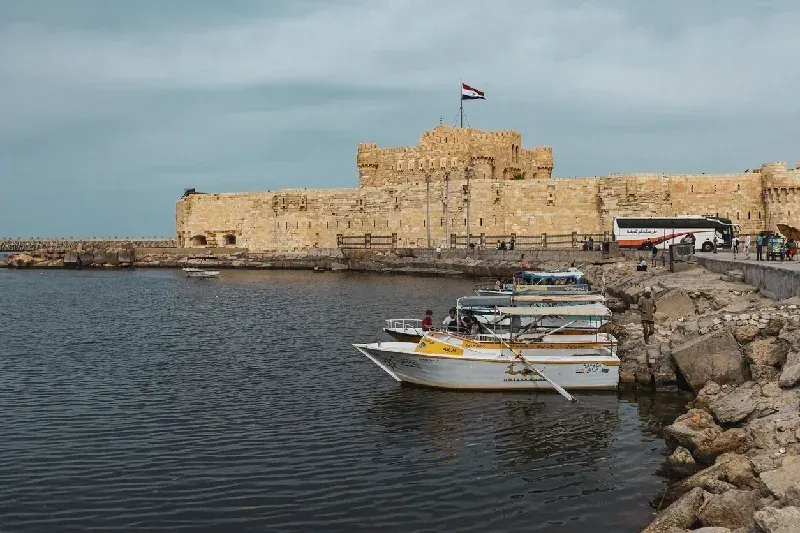 Mehrere Touristenboote nahe der Zitadelle von Qaitbay in Alexandria, Ägypten, einer antiken Festung an der Mittelmeerküste.